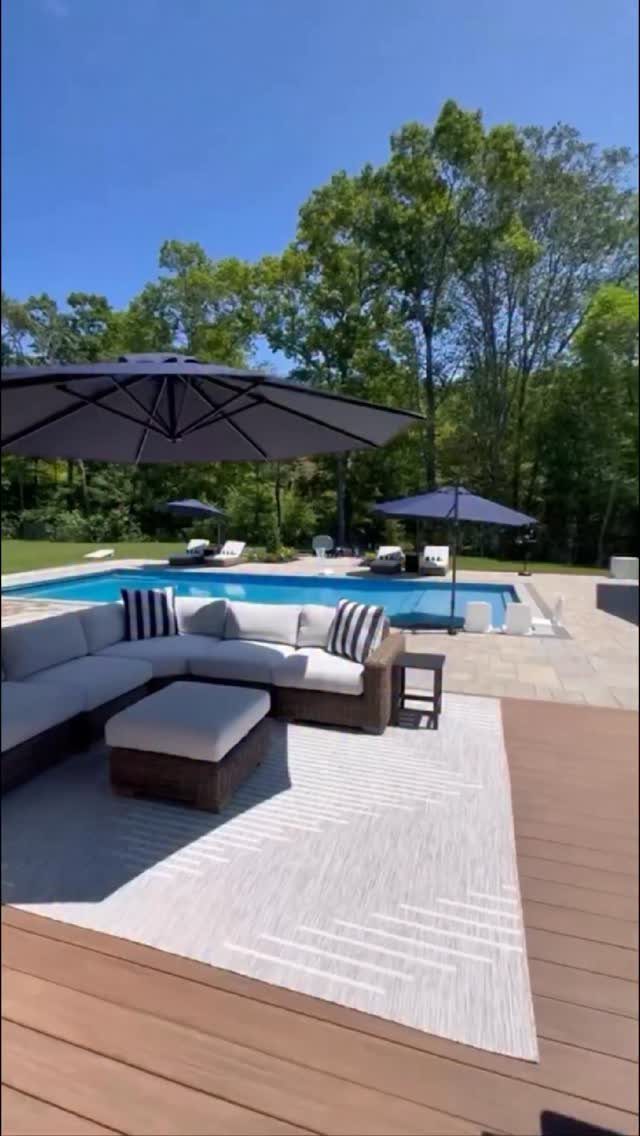 18 Big Backyard Garden Ideas for Every Budget 11 Outdoor lounge furniture with a sectional sofa and umbrella situated on a deck near a swimming pool.