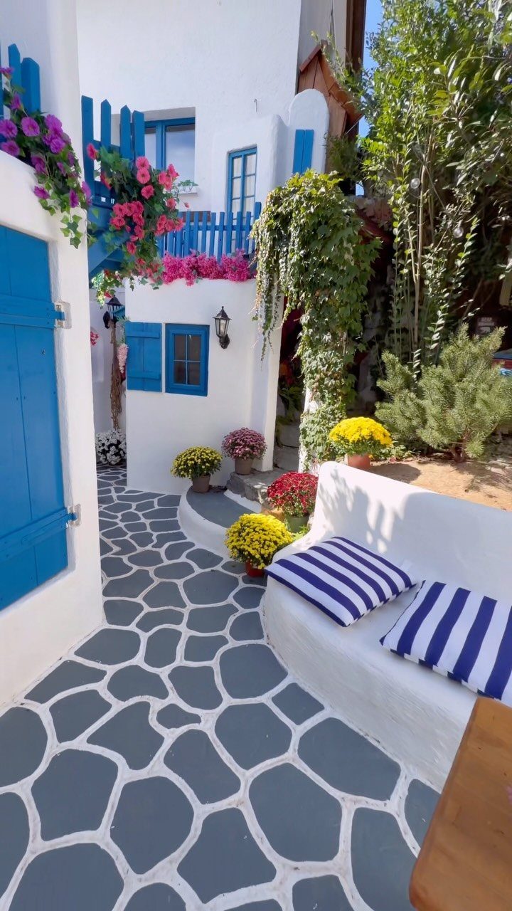 18 Big Backyard Garden Ideas for Every Budget 4 Grey flagstone patio with white built-in seating and blue accents in a Mediterranean setting.