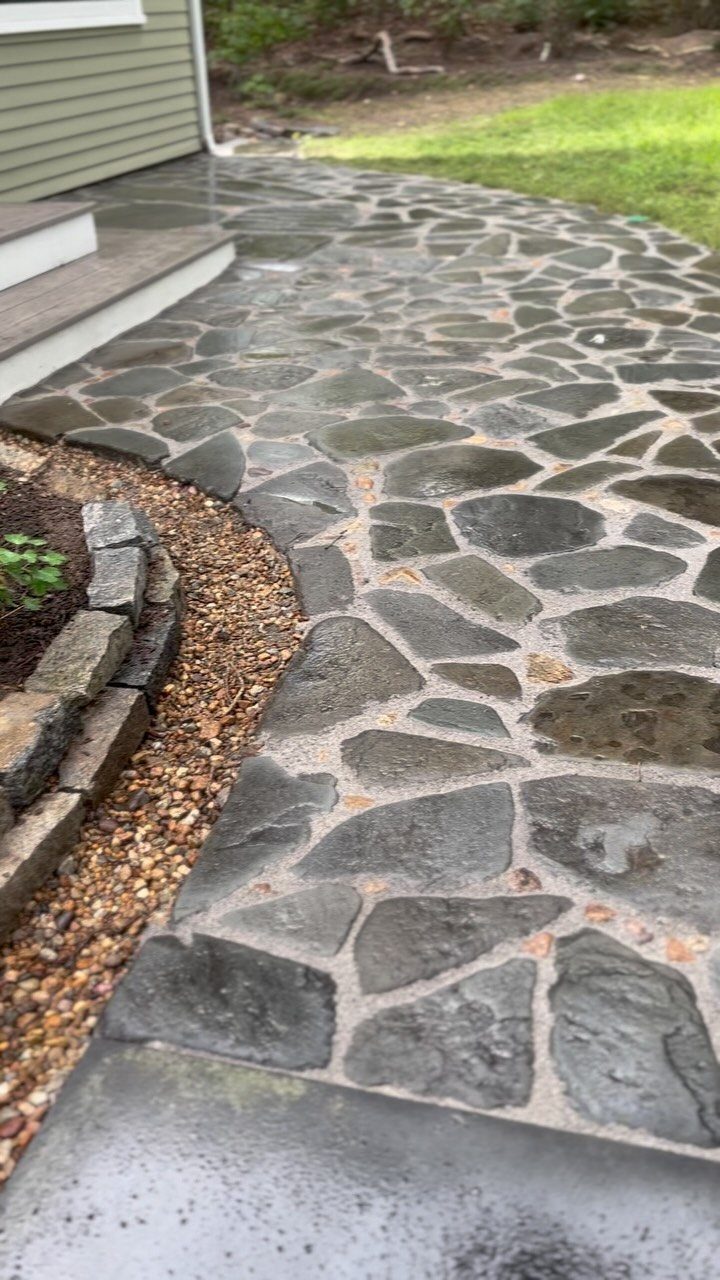 10 Cape Cod Front Yard Landscaping Ideas for Classic Charm 4 A curved natural stone pathway made of irregular grey stones set in mortar next to a garden bed.