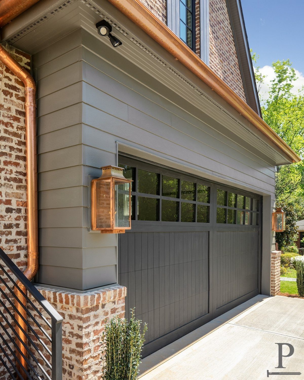 Craftsman Style Garage Doors: 8 Ideas from Carriage House to Modern Grey 7 A dark grey craftsman style garage door with glass window panes on a grey house.
