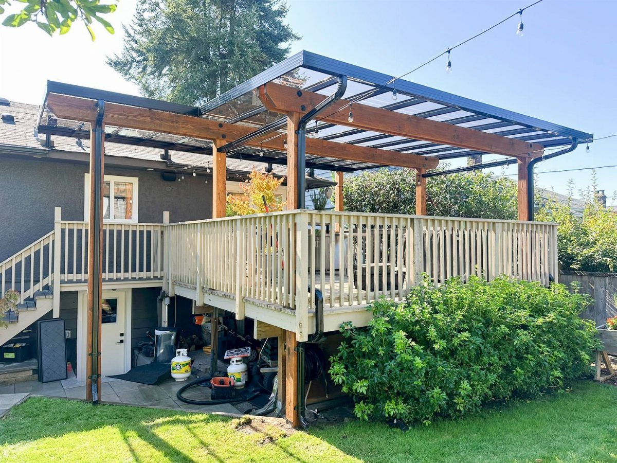 17 Deck Covering Ideas for Shade, Style & Rain Shelter 9 A wooden pergola with a black metal frame and clear polycarbonate roofing over a deck.
