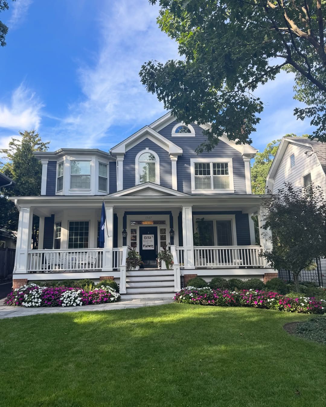 Deck on Front of House: 10 Ideas for Welcoming Style 8 A blue two-story house with white pillars and steps leading to a front porch.