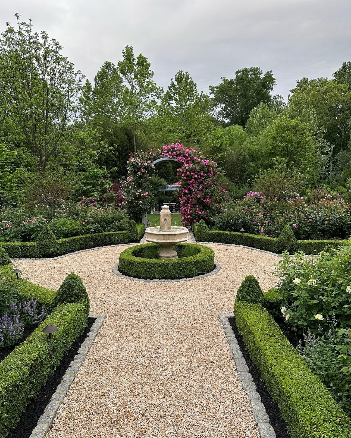English Garden Front Yard: 11 Ideas for Curb Appeal 5 Light tan pea gravel path bordered by low green hedges in a lush garden setting.
