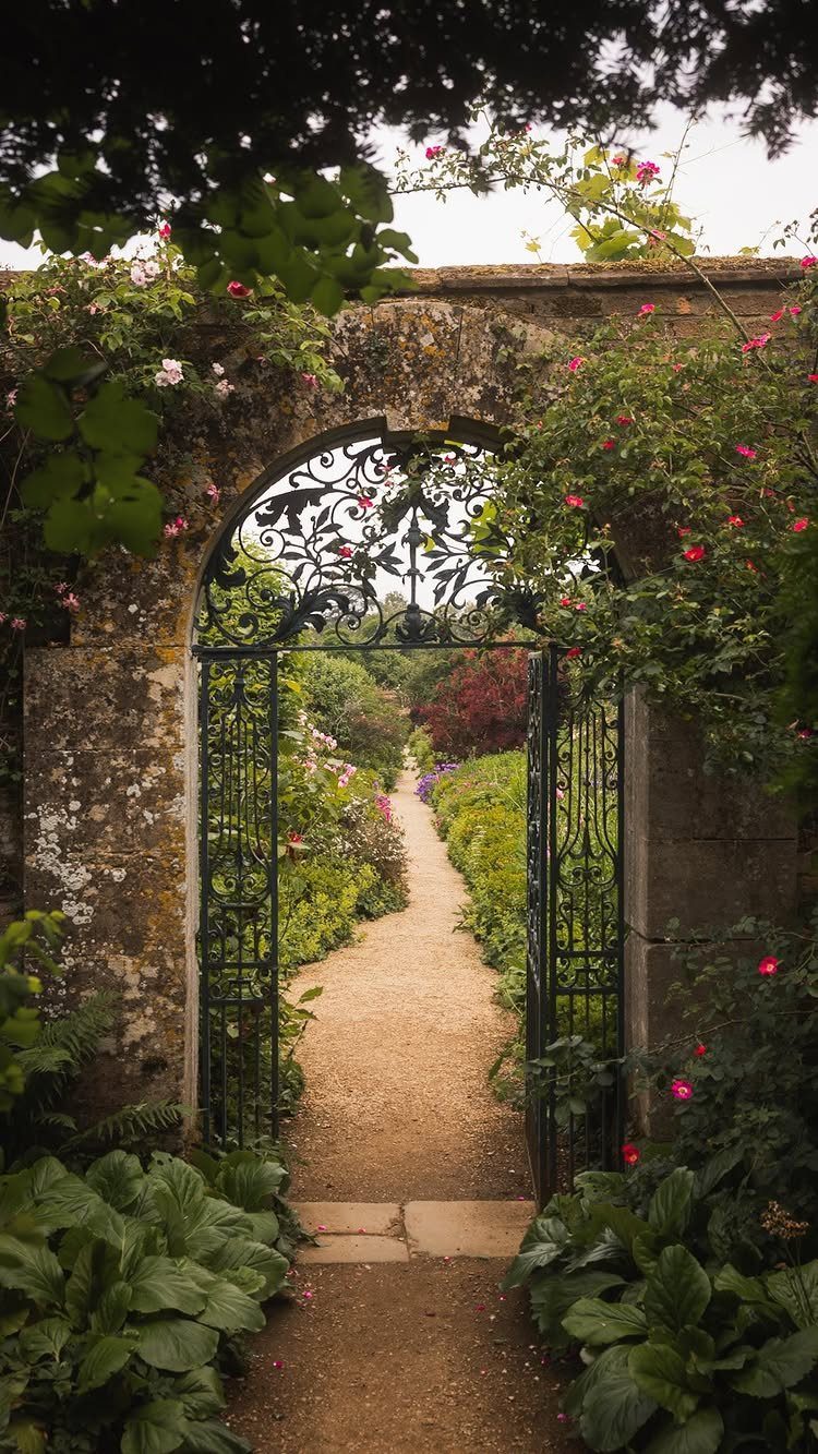 English Garden Front Yard: 11 Ideas for Curb Appeal 7 Wrought iron gate opening onto a gravel path through a lush, flowering English garden.