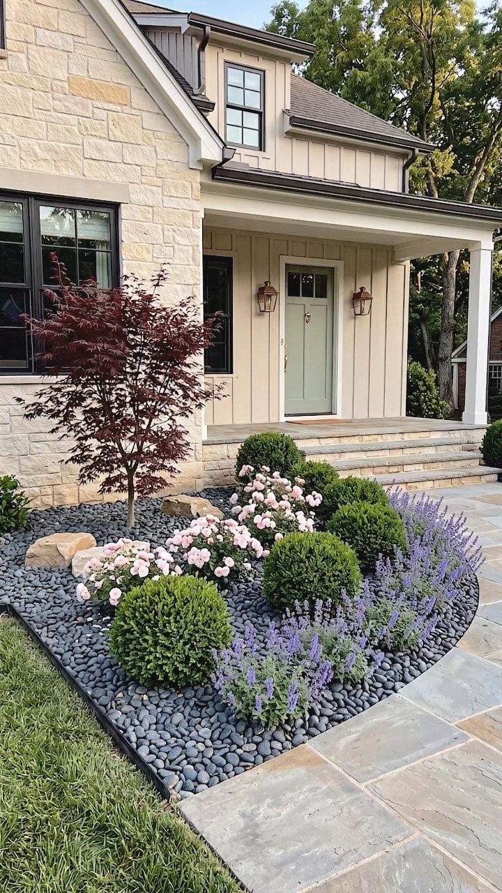 A landscaped garden bed with shrubs, lavender, and a red maple tree in front of a house.