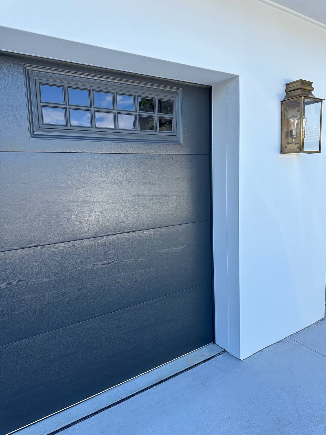 9 Garage Door Makeover Ideas for Instant Curb Appeal 1 A dark blue garage door featuring a row of small glass window panes at the top.
