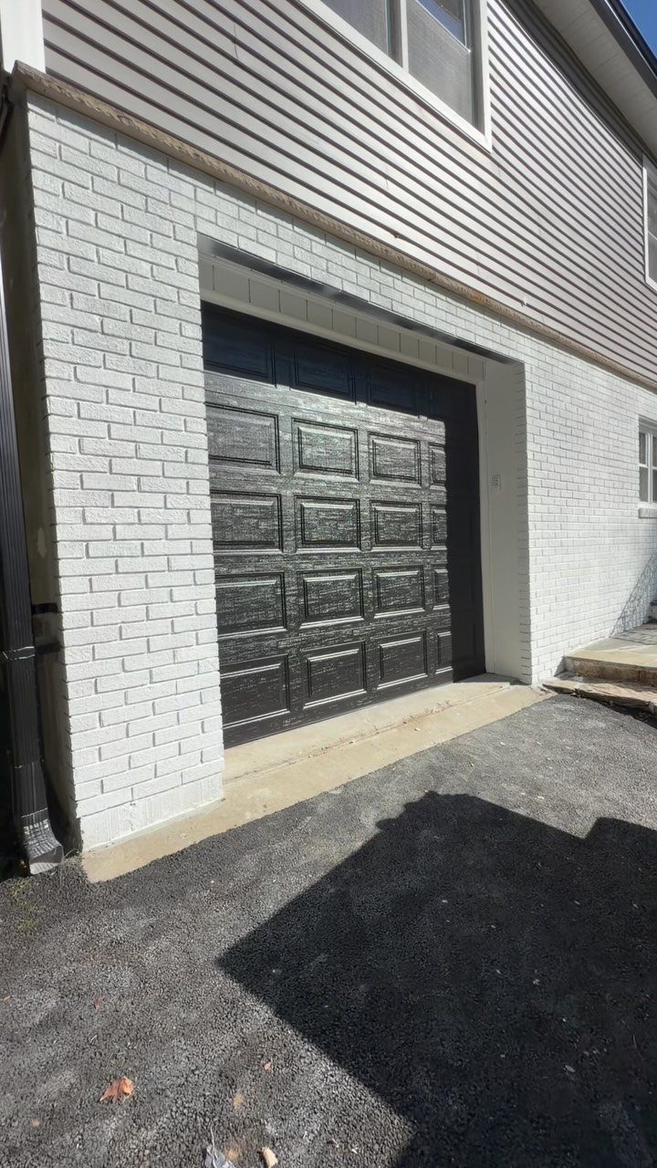 9 Garage Door Makeover Ideas for Instant Curb Appeal 3 A black paneled garage door installed in a white brick exterior wall.