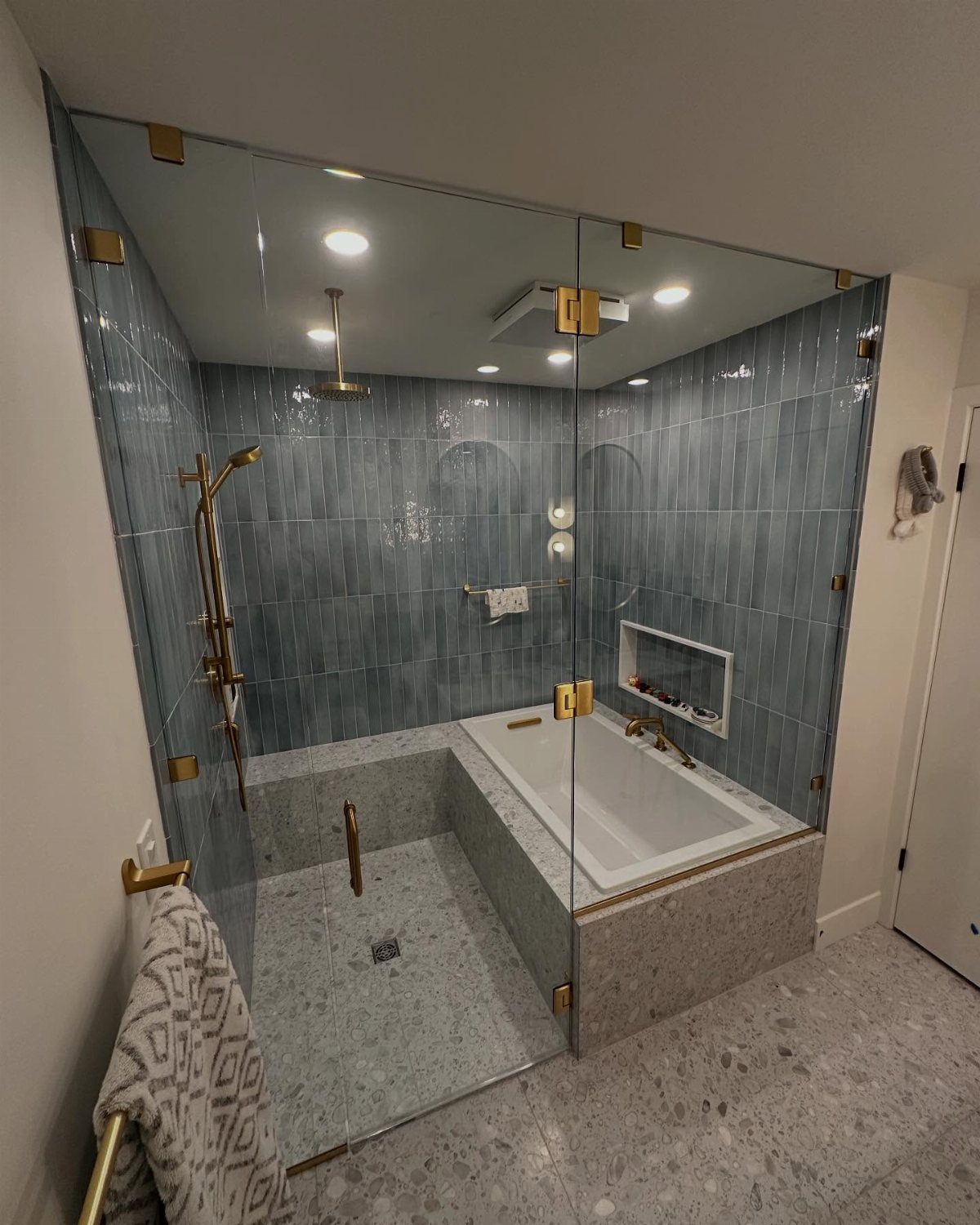 Turning a Garage to a Studio Apartment: 9 Layouts That Work 3 Modern bathroom with blue tiled walls, a glass shower enclosure, and a built-in white bathtub.