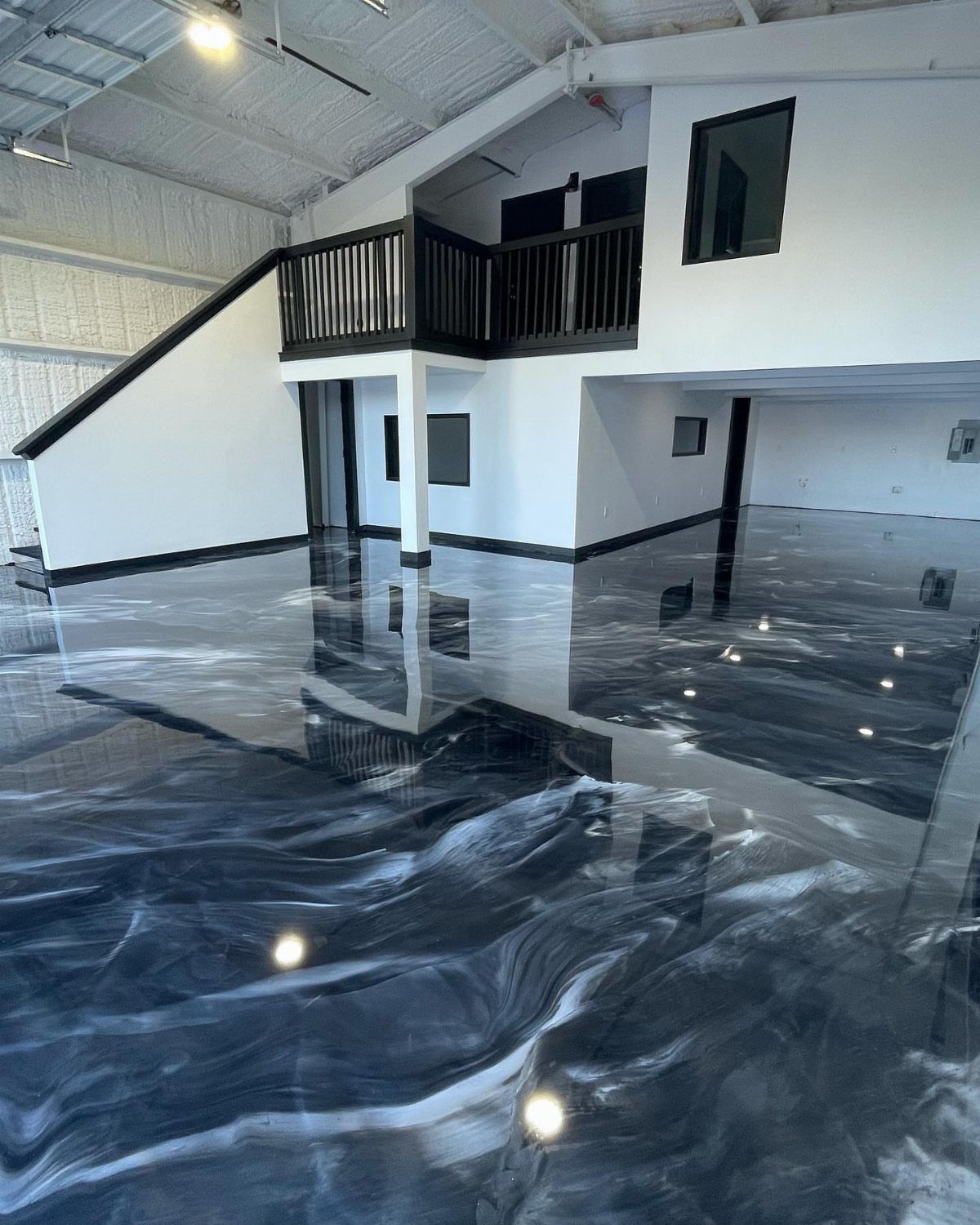 Turning a Garage to a Studio Apartment: 9 Layouts That Work 4 Polished black and white swirling epoxy flooring in a large, modern white room.