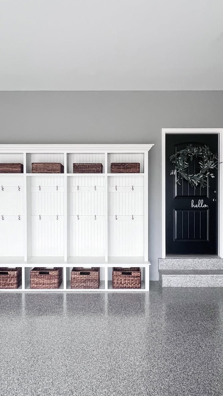 9 Garage Paint Colors for Doors, Floors, Walls and Ceiling 2 Speckled grey epoxy garage floor in a clean entryway with white storage cubbies and a black door.