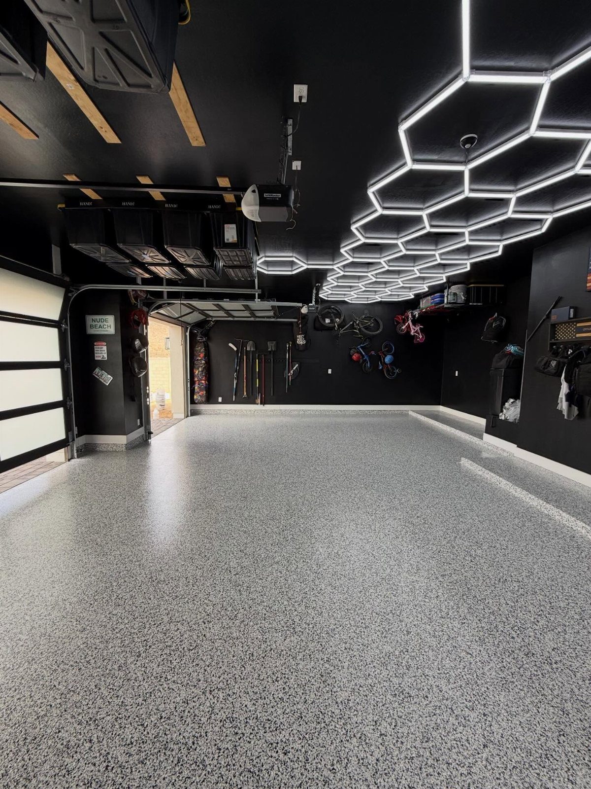 9 Garage Paint Colors for Doors, Floors, Walls and Ceiling 3 A modern garage with black walls and a large white hexagonal LED light fixture on the ceiling.