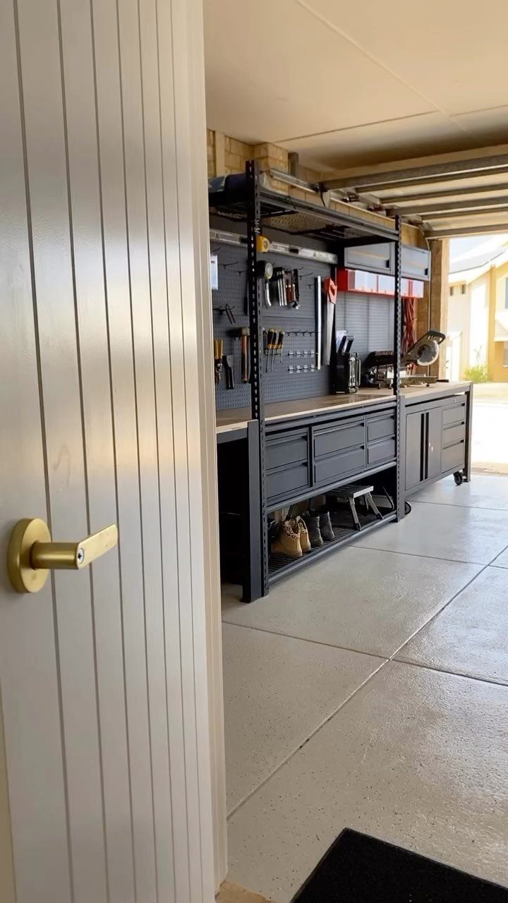 Black metal garage workbench with tools and shoes stored on the bottom shelf.