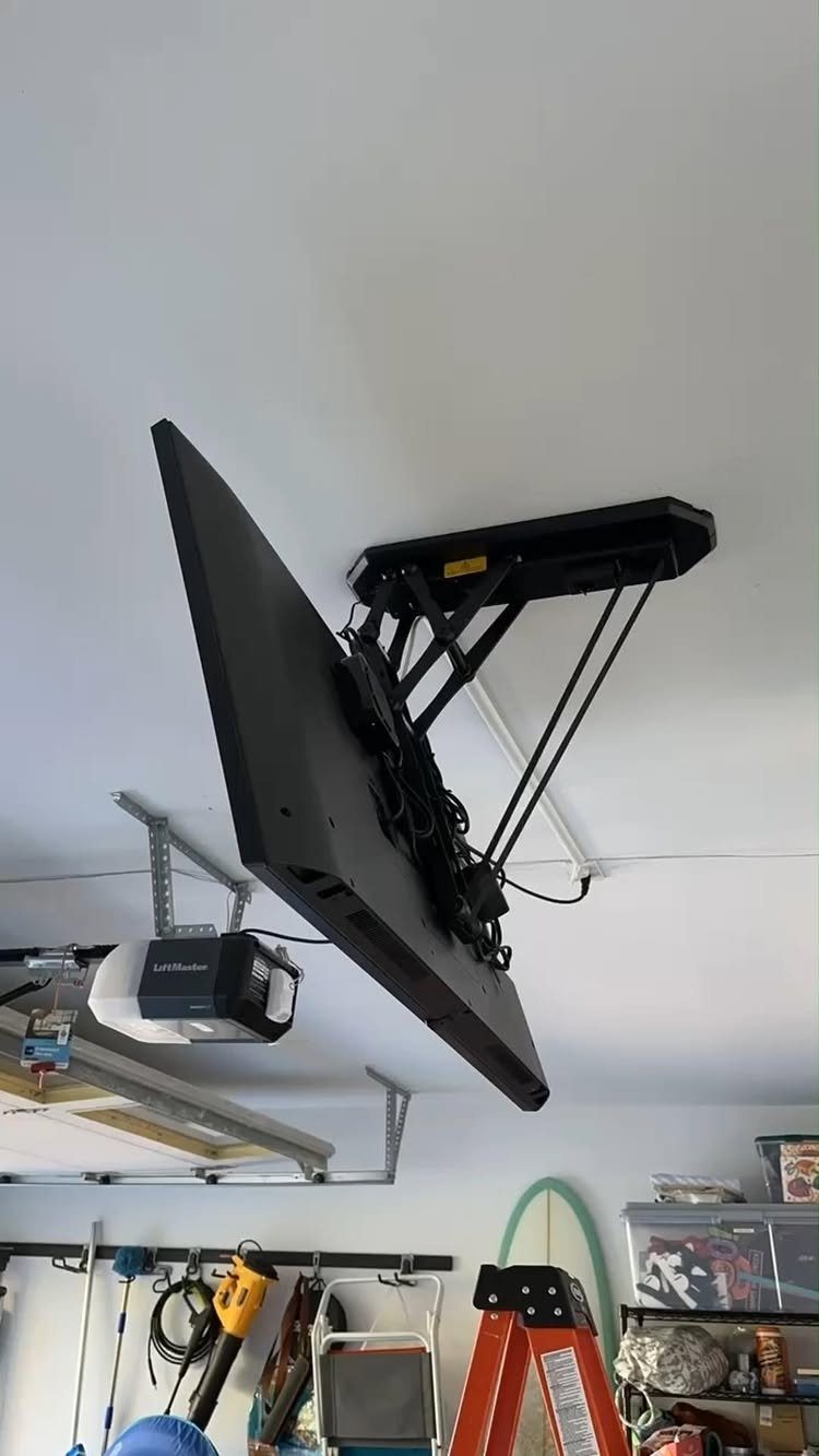 11 Garage Storage Inspiration and Ceiling Systems That Actually Fit 11 A black television mounted to a garage ceiling using a mechanical lift system.