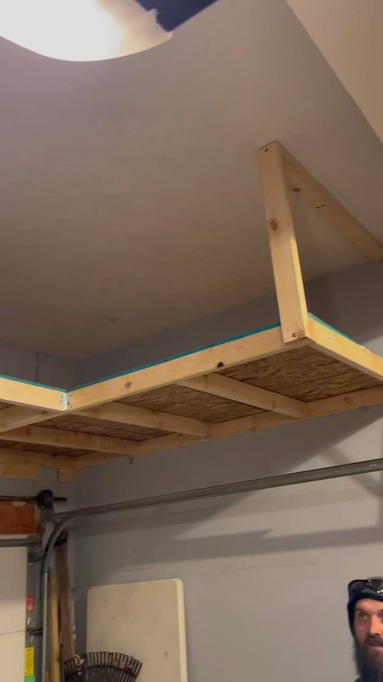 11 Garage Storage Inspiration and Ceiling Systems That Actually Fit 7 A custom wooden plywood storage platform mounted to a garage ceiling with timber framing.