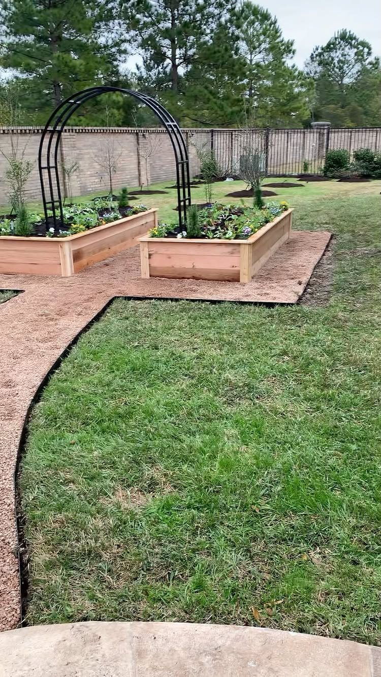 Garden Plans and Layouts: 7 Ideas for Small and Large Spaces 5 Two symmetrical wooden raised garden beds separated by a black metal archway on a gravel path.