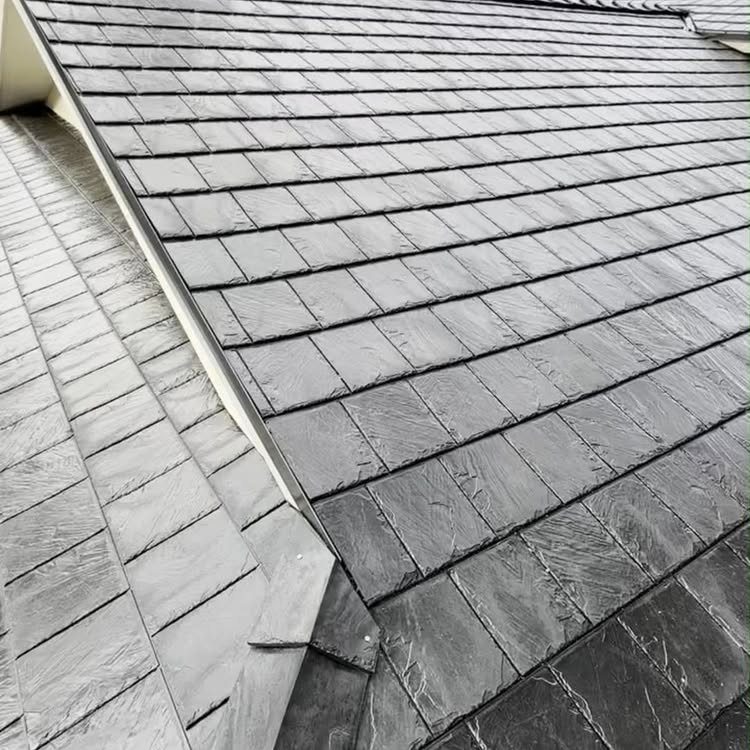 Dark grey textured slate shingles covering a residential roof surface in an overlapping pattern.