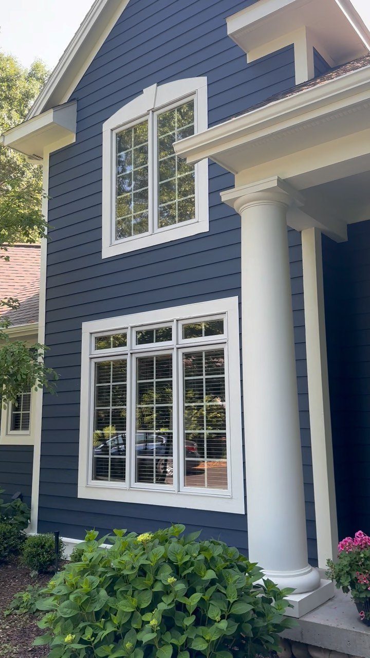 Blue house siding with white window trim and a large white porch column.