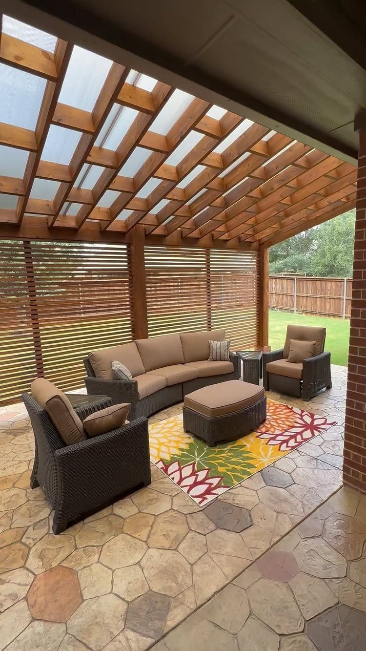 18 Large Yard Ideas for Patios, Pools, Outdoor Kitchens & More 4 A wooden pergola with a translucent roof shading a stone patio with outdoor lounge furniture.