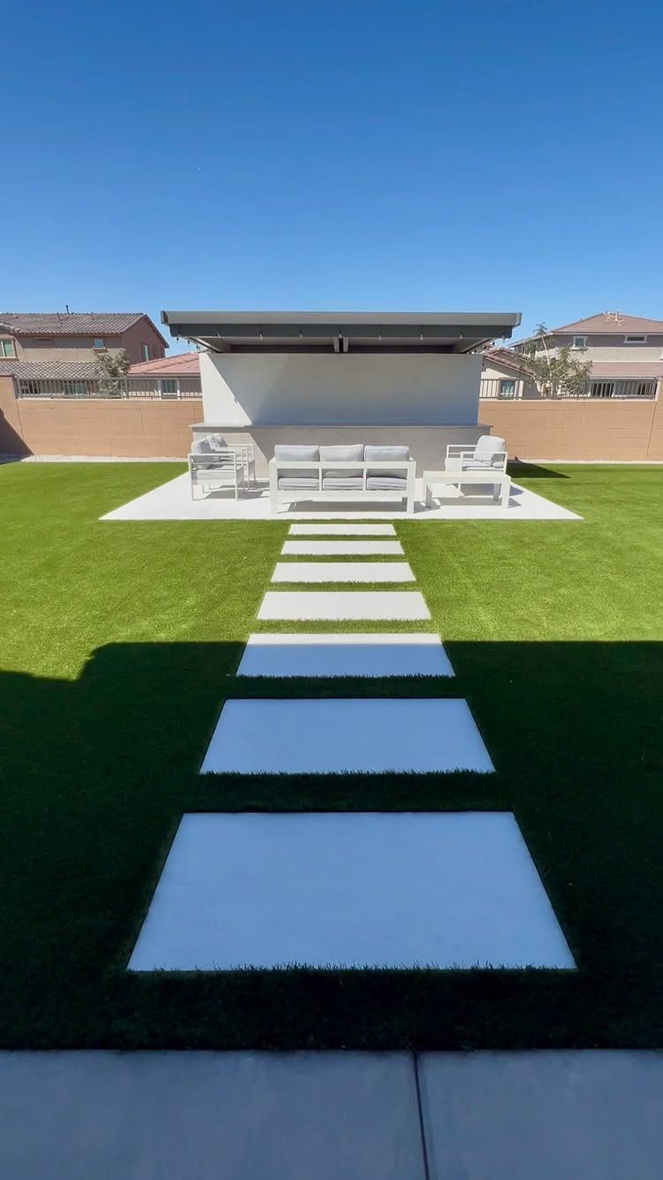 18 Large Yard Ideas for Patios, Pools, Outdoor Kitchens & More 18 White rectangular stepping stones lead across a green lawn toward a modern outdoor seating area.