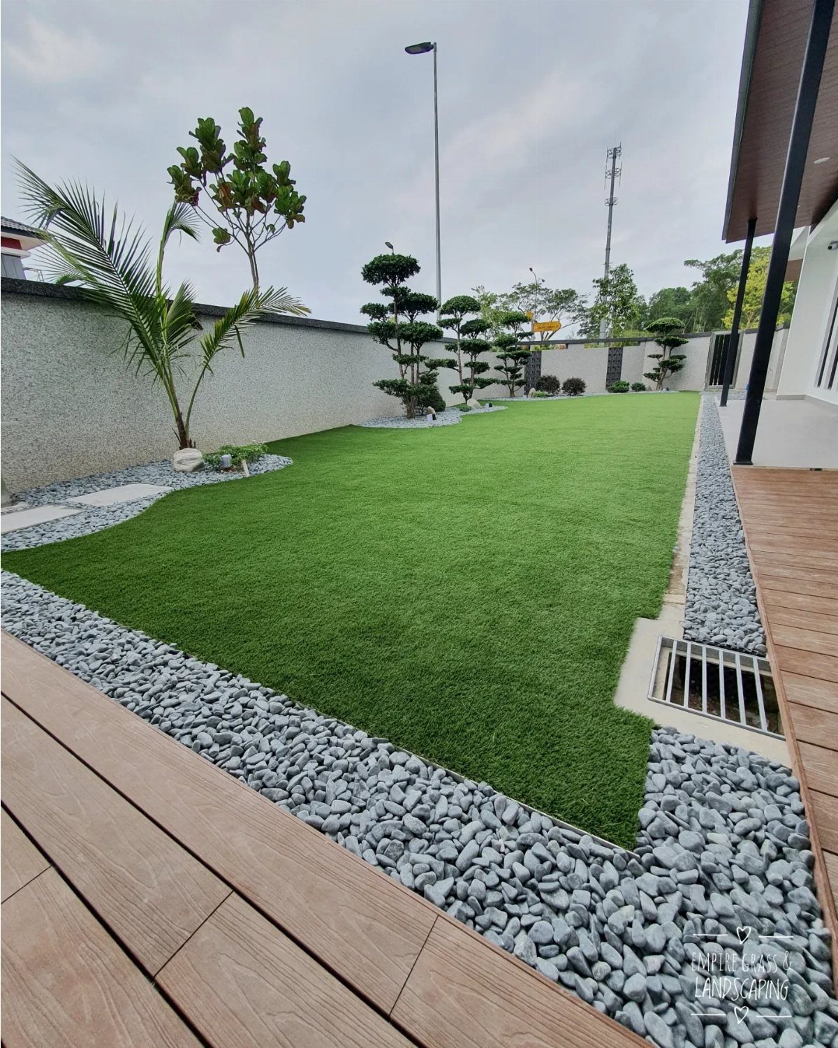 18 Large Yard Ideas for Patios, Pools, Outdoor Kitchens & More 13 Green artificial turf bordered by grey stones and a wooden deck in a modern yard.