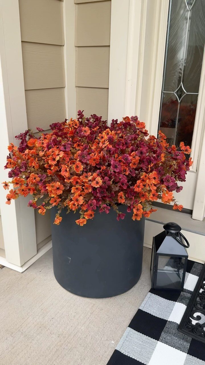 Low Planter Ideas: 8 Creative Designs for Small Spaces 7 A large grey planter filled with vibrant orange and red autumn flowers on a porch.