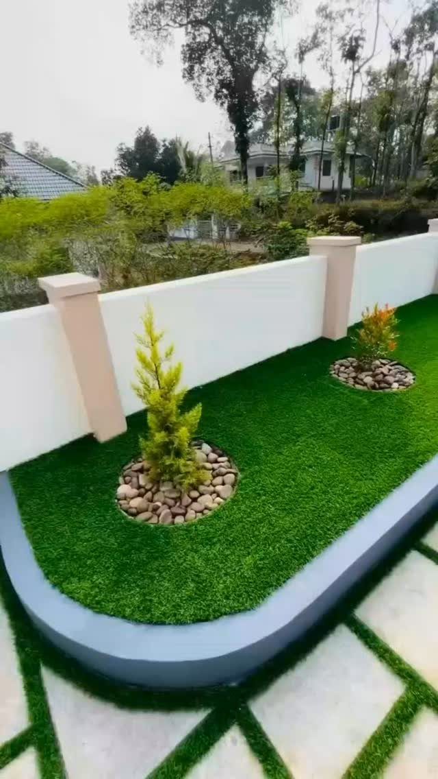 Modern Landscape Design: 12 Ideas for a Contemporary Yard 4 Artificial turf garden with small shrubs in stone beds and a white boundary wall.