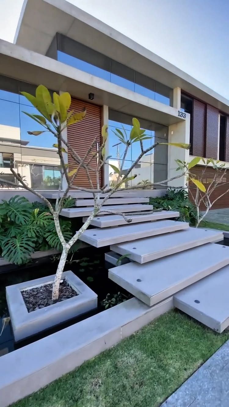 Modern Landscape Design: 12 Ideas for a Contemporary Yard 1 Concrete floating steps over a dark water feature leading to a modern house entrance.