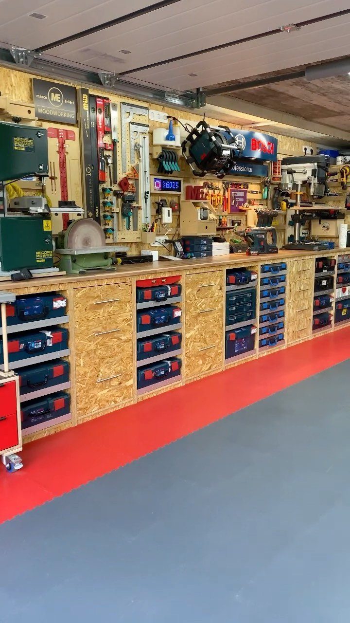12 One Car Garage Workshop Layout Ideas That Save Space 1 A long wooden workbench with blue tool drawers and various power tools in a garage workshop.