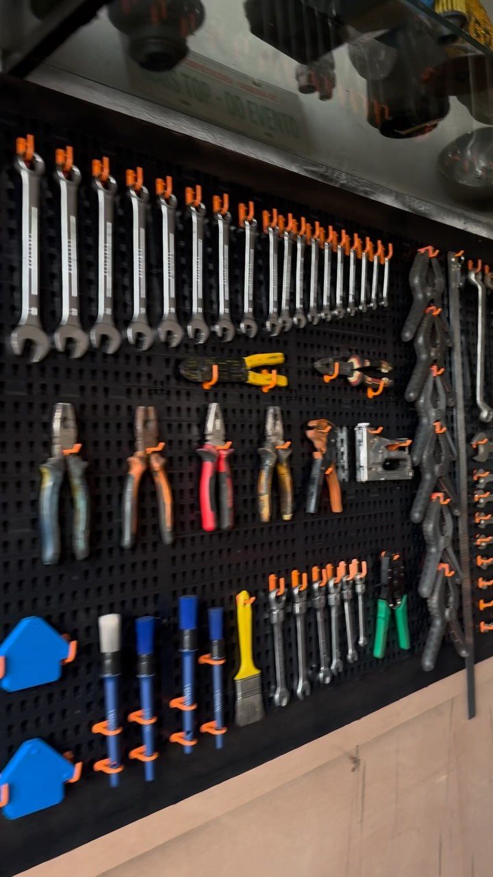 12 One Car Garage Workshop Layout Ideas That Save Space 6 Various hand tools like wrenches and pliers organized on a black pegboard with orange holders.