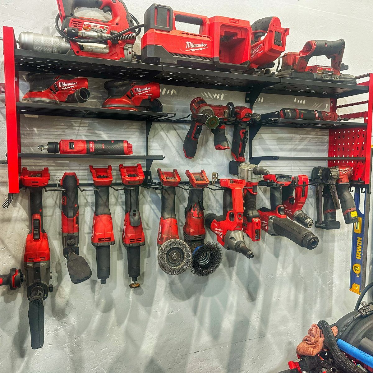 12 One Car Garage Workshop Layout Ideas That Save Space 3 Red power tools hanging on black metal wall-mounted racks in a workshop.