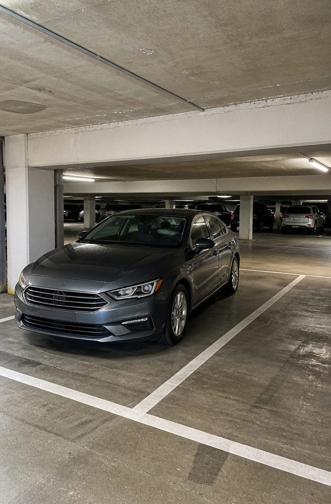 Parking Garage Fits: Clearance Heights by Structure Type for Tall Vehicles 2 A standard sedan parked in a dimly lit garage with a 7'0" clearance sign.