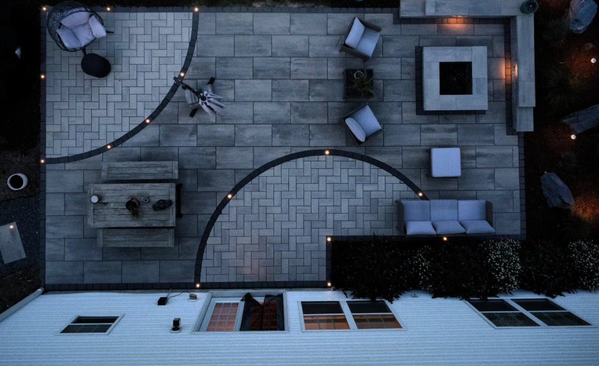 12 Paver Patio Ideas for Fire Pits, Poolside Lounges & Outdoor Rooms 7 Aerial view of a modern grey stone paver patio with outdoor furniture and a fire pit.