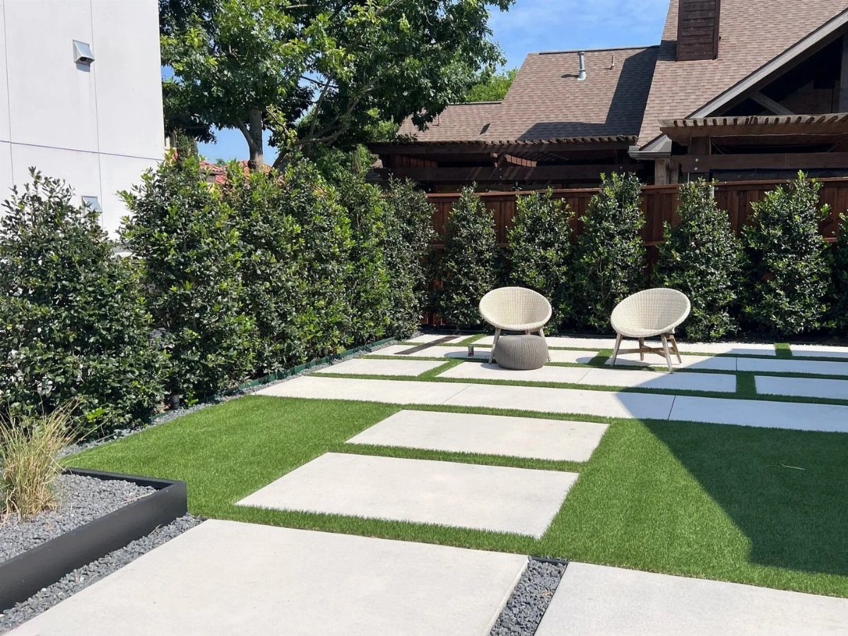 12 Paver Patio Ideas for Fire Pits, Poolside Lounges & Outdoor Rooms 8 Large rectangular concrete pavers arranged in a grid with green turf inlays in a backyard.