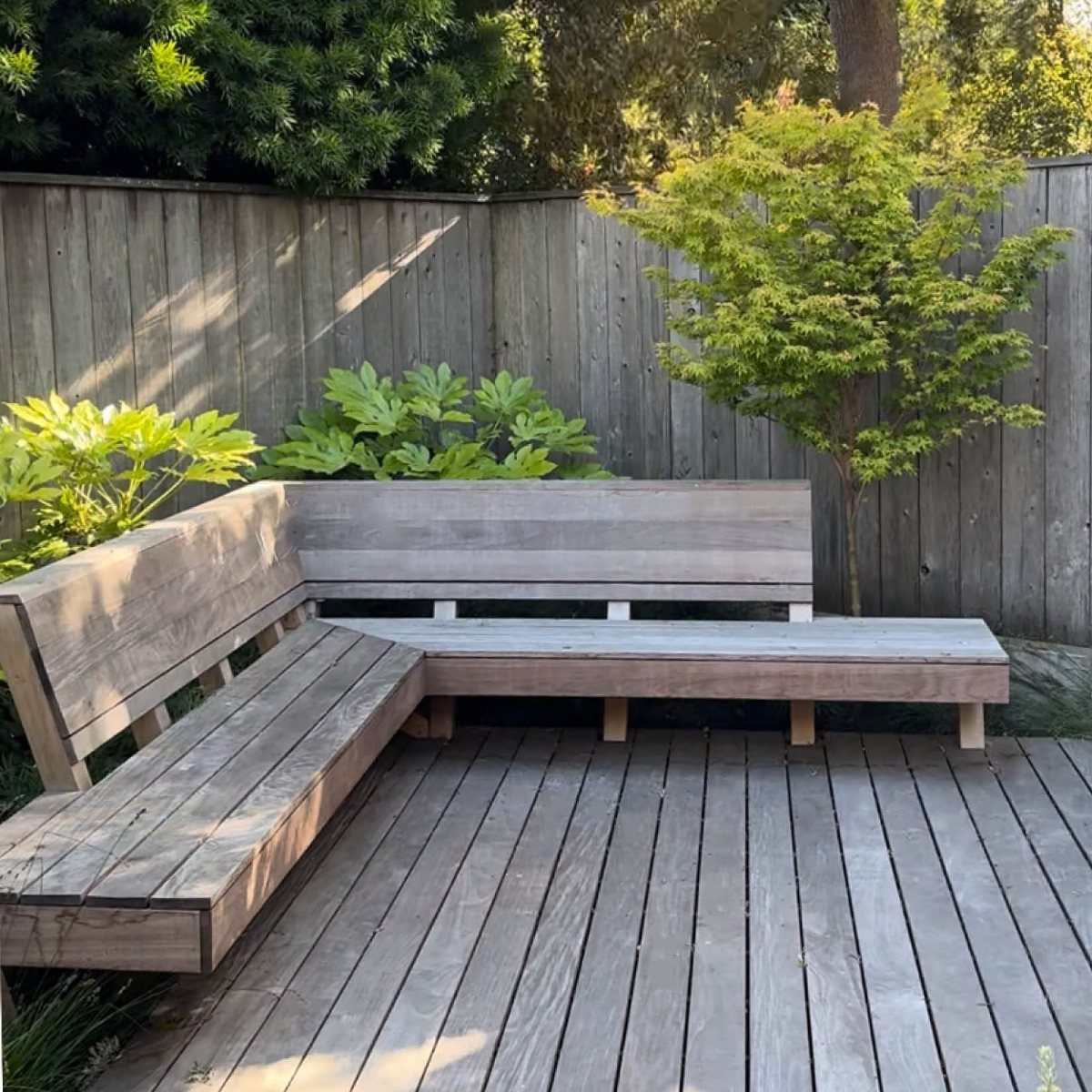19 Small Backyard Wooden Deck Ideas 6 L-shaped built-in wooden bench integrated into a grey weathered wooden backyard deck.