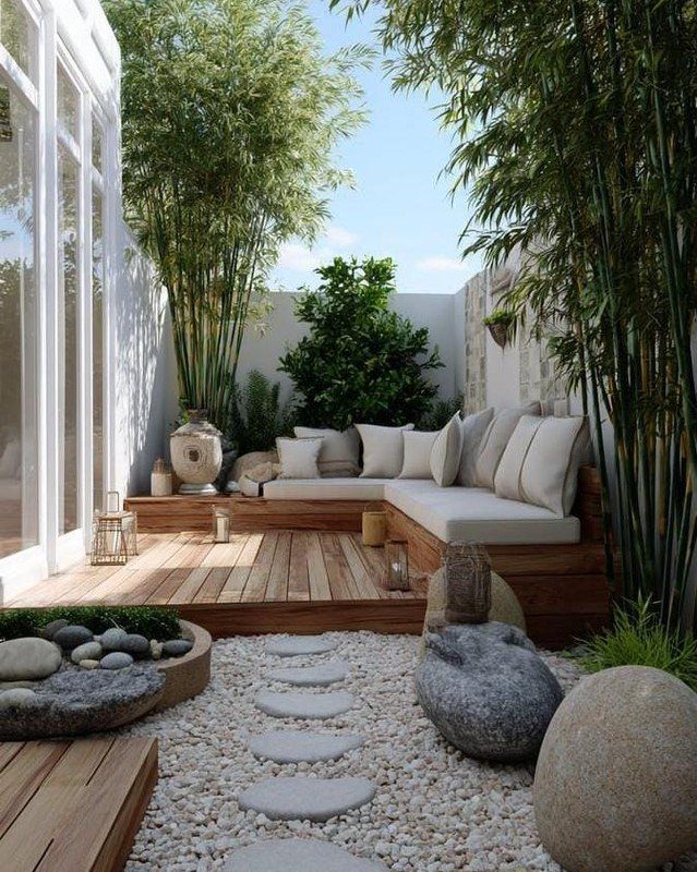 19 Small Backyard Wooden Deck Ideas 5 Built-in wooden deck seating with white cushions surrounded by tall bamboo and white walls.