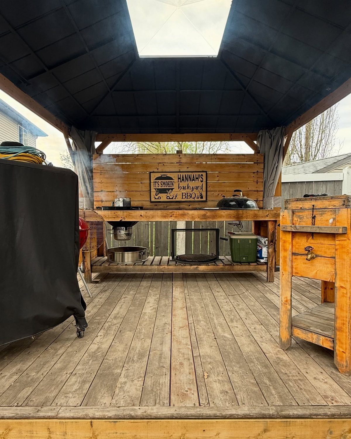 19 Small Backyard Wooden Deck Ideas 11 Wooden BBQ station with a grill and sign located on a wooden deck under a canopy.
