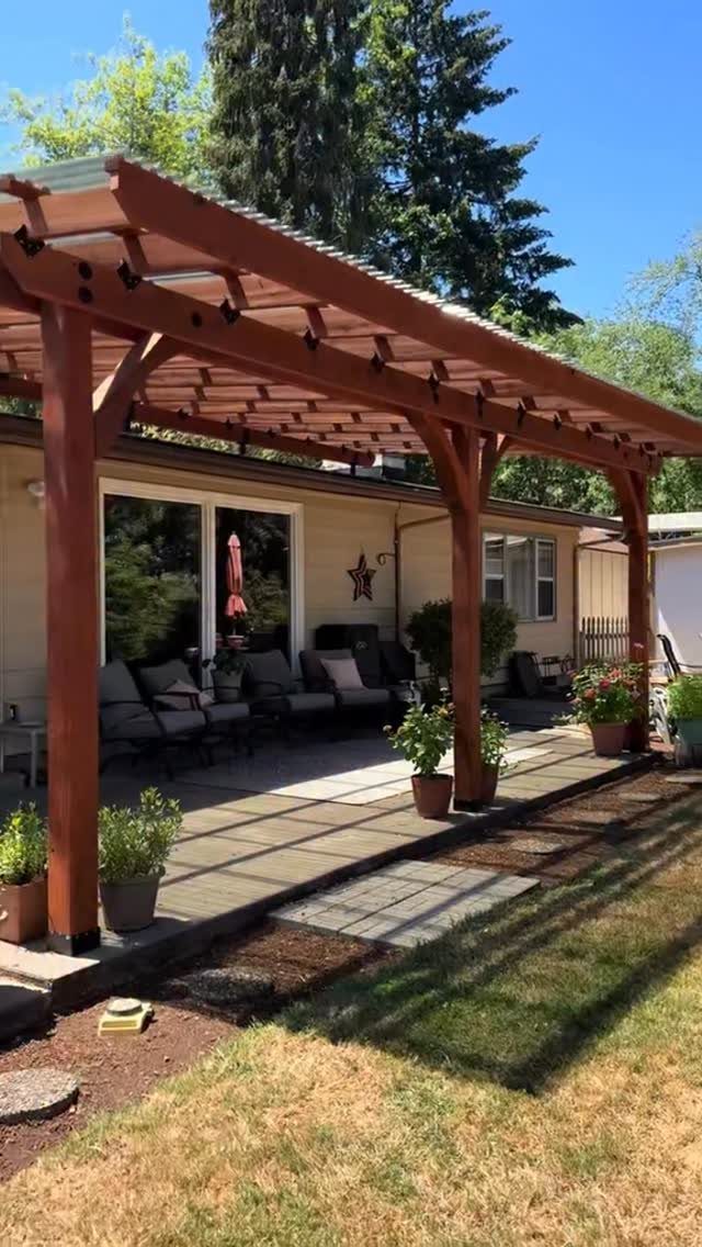 19 Small Backyard Wooden Deck Ideas 7 A large reddish-brown wooden pergola covering a patio with outdoor seating and potted plants.