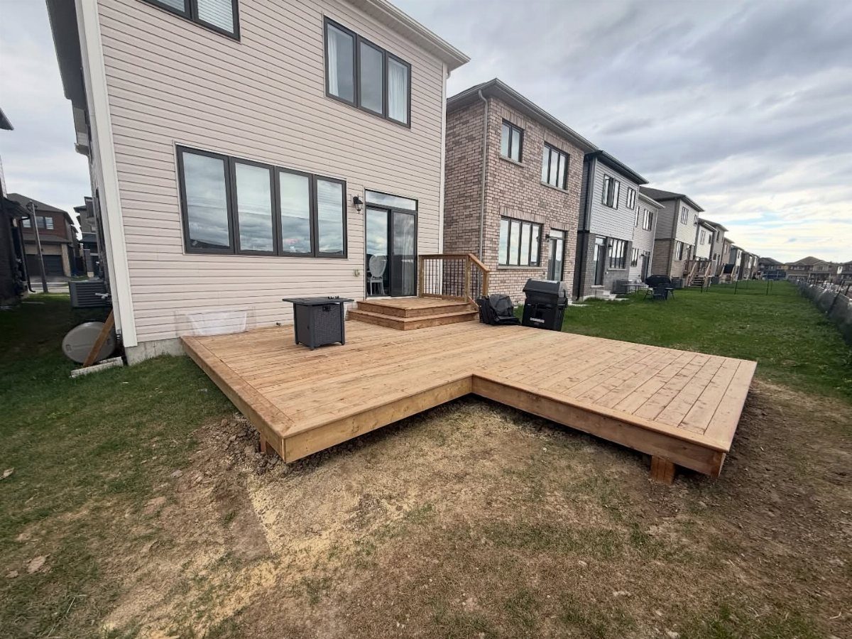 19 Small Backyard Wooden Deck Ideas 4 L-shaped wooden deck installed on a grassy lawn next to a modern house.