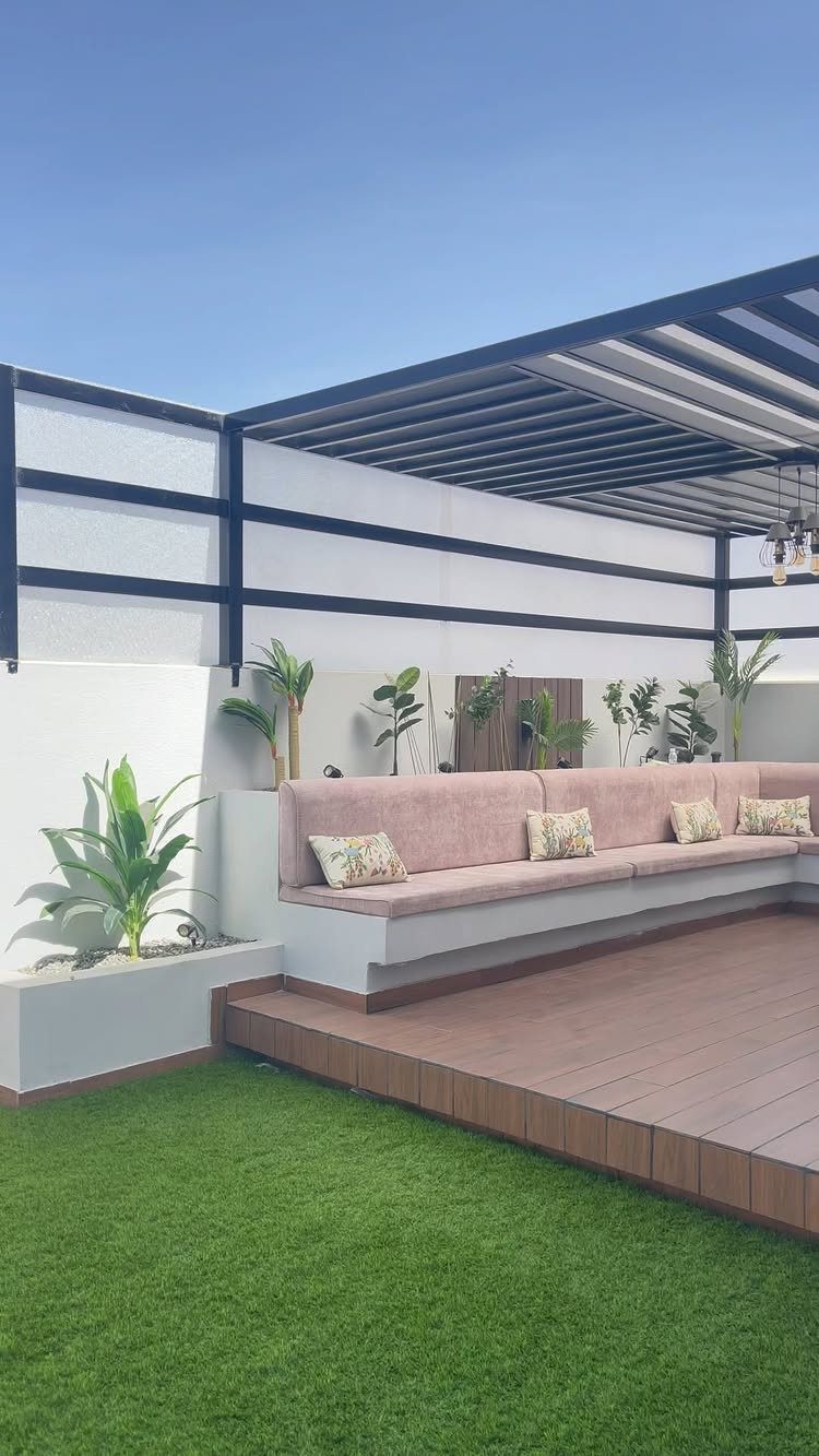 19 Small Garden Design Ideas with Built-In Planning Tips 6 Built-in outdoor bench with pink cushions on a wooden deck under a pergola.