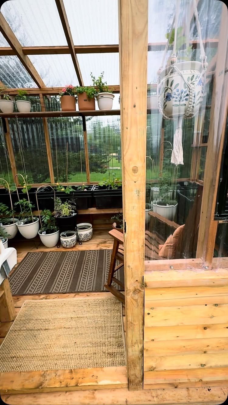 19 Small Garden Design Ideas with Built-In Planning Tips 15 Potted plants arranged on shelves and the floor inside a wooden greenhouse structure.