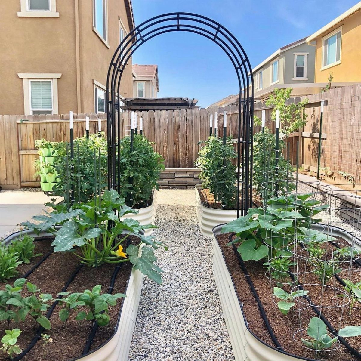 19 Small Garden Design Ideas with Built-In Planning Tips 13 White corrugated metal raised garden beds filled with green vegetables in a backyard garden.
