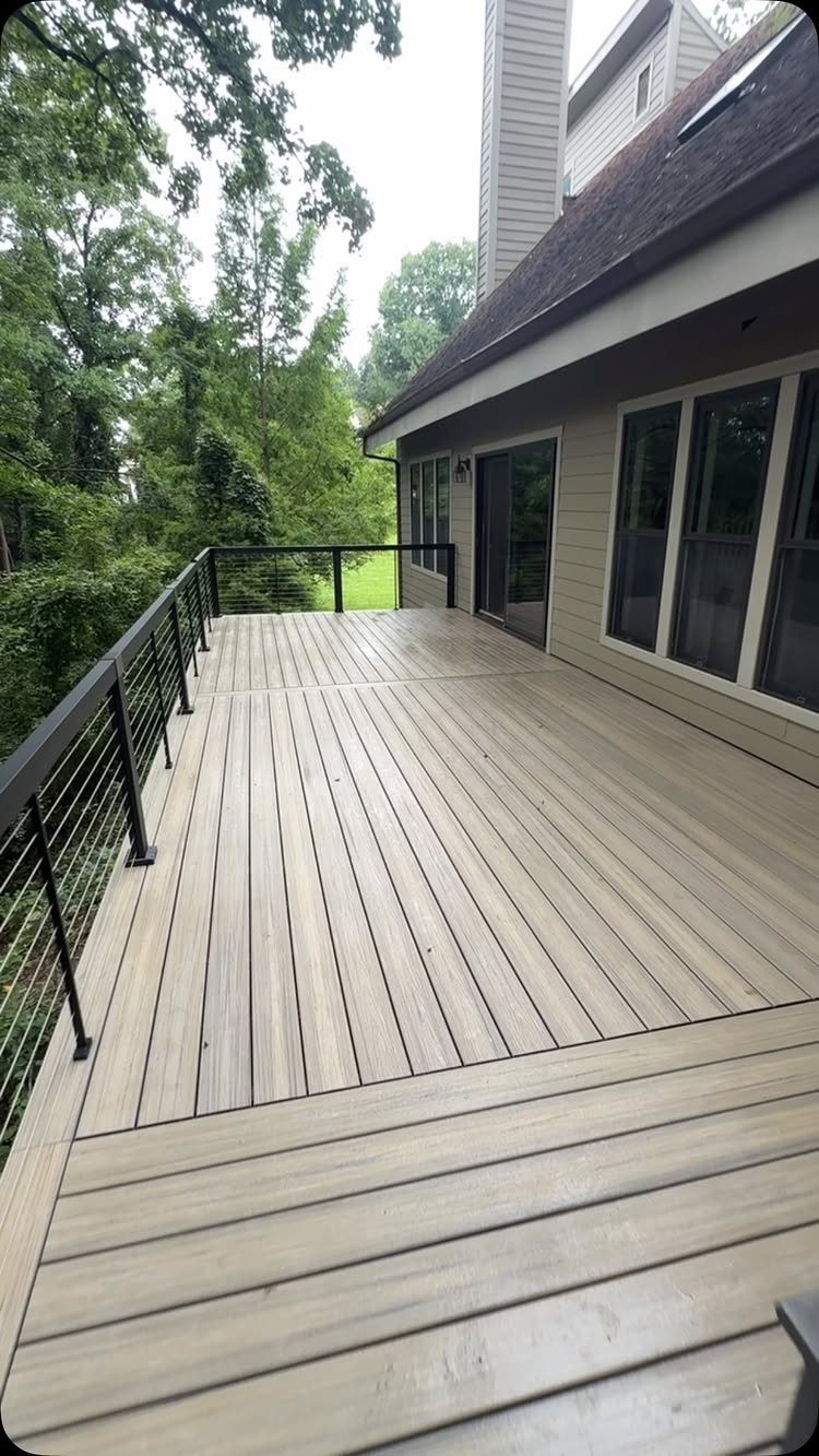 12 Trex Deck Floor Designs for Picture Frames to Herringbone 3 Light grey composite decking boards meeting a black metal railing with cable infills on a backyard deck.
