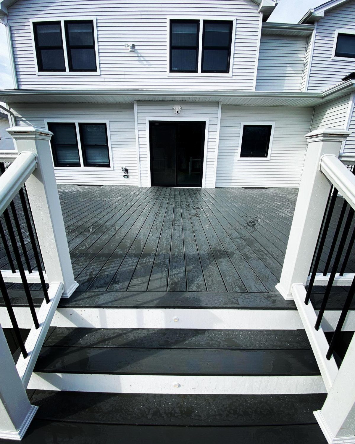 12 Trex Deck Floor Designs for Picture Frames to Herringbone 12 Dark grey wooden deck with white railings attached to a white house with black windows.