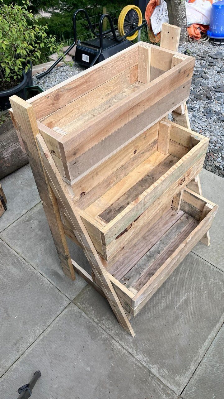 Wood Planter Box: 11 Ideas from Scrap Builds to Built-In Benches 6 Three tiered pine wood planter boxes arranged on a wooden stand outdoors.