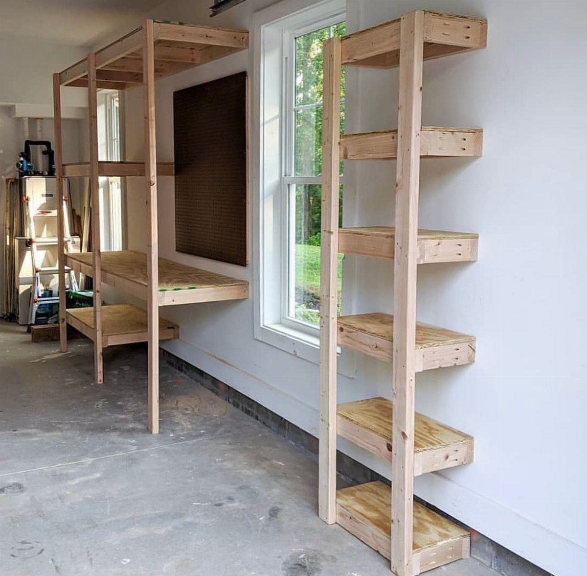 Wooden shelving units installed against a white wall in a garage setting.