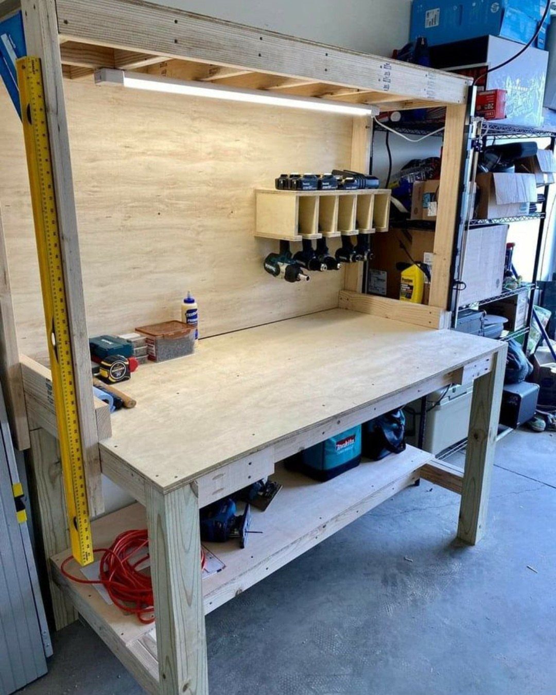 A wooden DIY workbench with integrated storage shelves and a drill organizer in a garage.