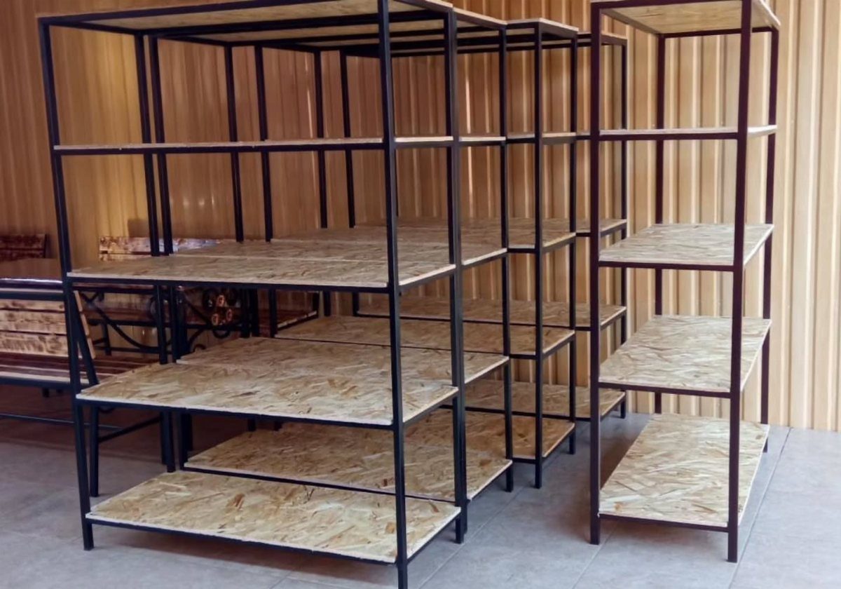 Three black metal freestanding shelving units with OSB wood shelves standing on a tiled floor.