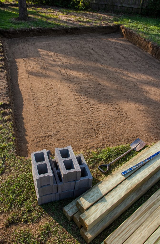 How to Build a Wooden Shed: 7 Steps from Foundation to Finish 2 Ground prepared with concrete blocks and lumber for a shed foundation.